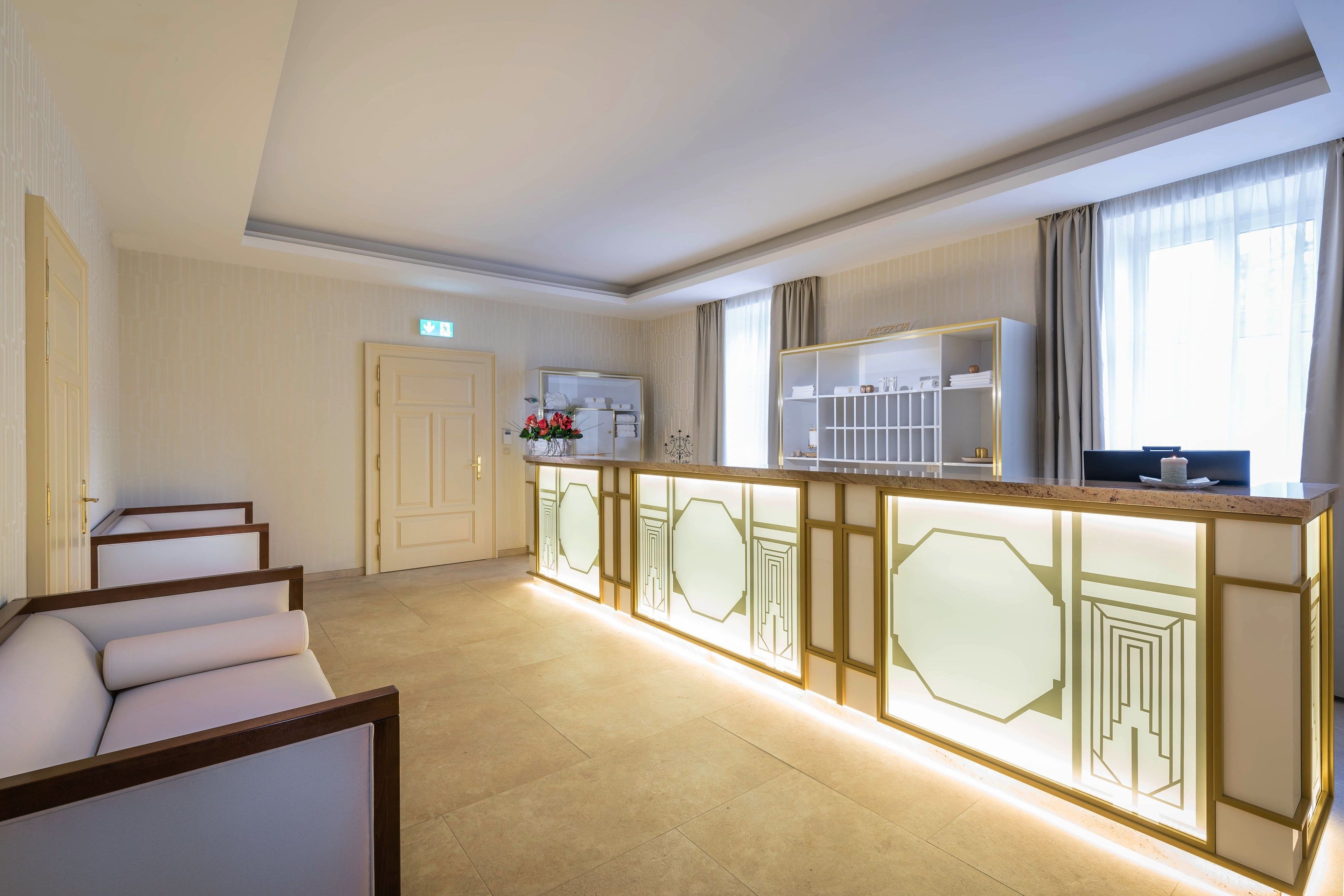 A modern hotel lobby with a reception desk, seating area, and a large window with curtains.