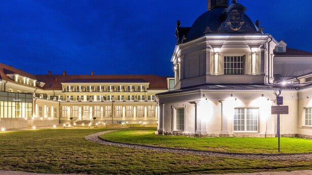 Um edifício histórico com uma cúpula imponente e um pátio bem iluminado à noite.