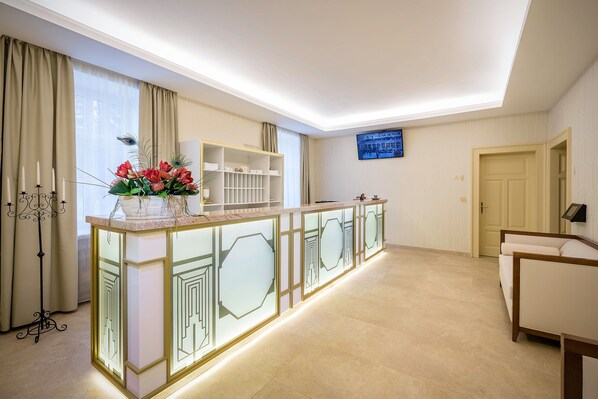 A modern reception area with a glass partition, a decorative plant, and a television mounted on the wall. - Royal Palace (Turcianske Teplice)