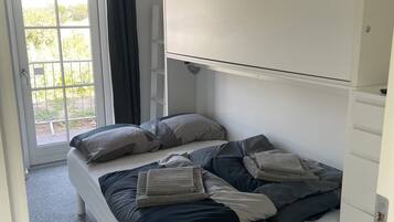 A bedroom with a bed, a wardrobe, and a sliding glass door leading to an outdoor area.