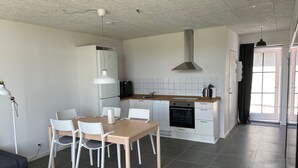 Ett modernt kök med vita skåp, en inbyggd ugn och en matplats med bord och stolar.
