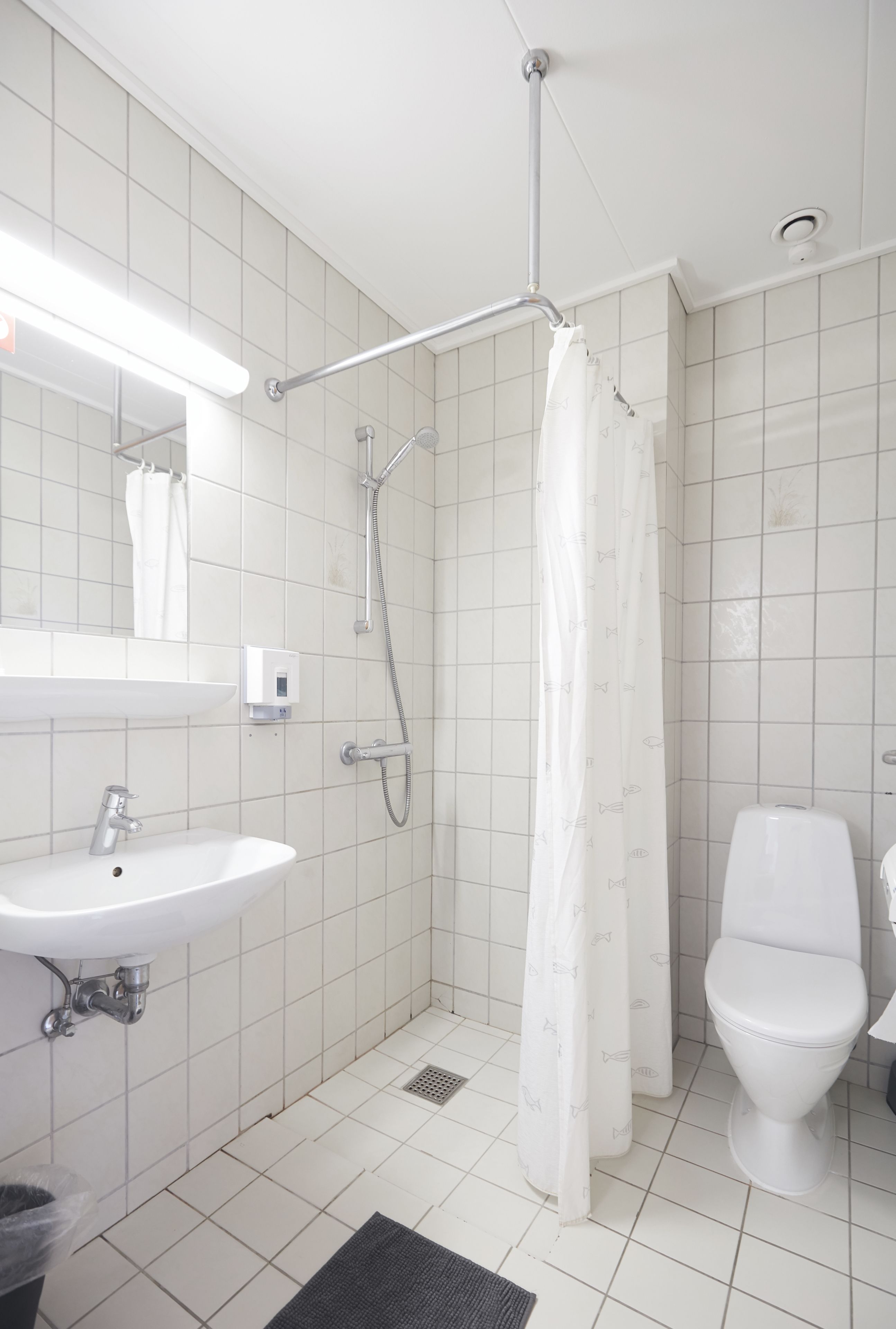 A bathroom with a shower, toilet, sink, and a mirror.