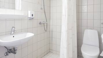 Un baño con ducha, inodoro, lavamanos y espejo.