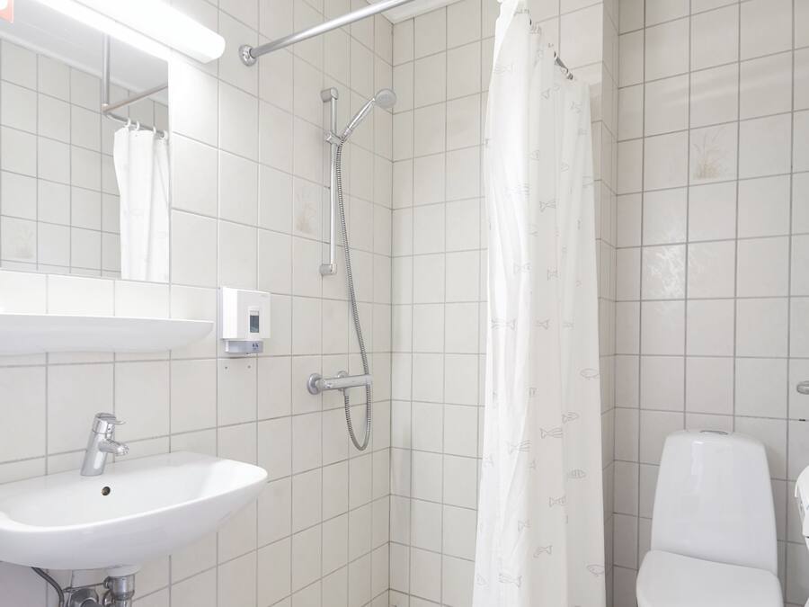 Un baño con ducha, inodoro, lavamanos y espejo.