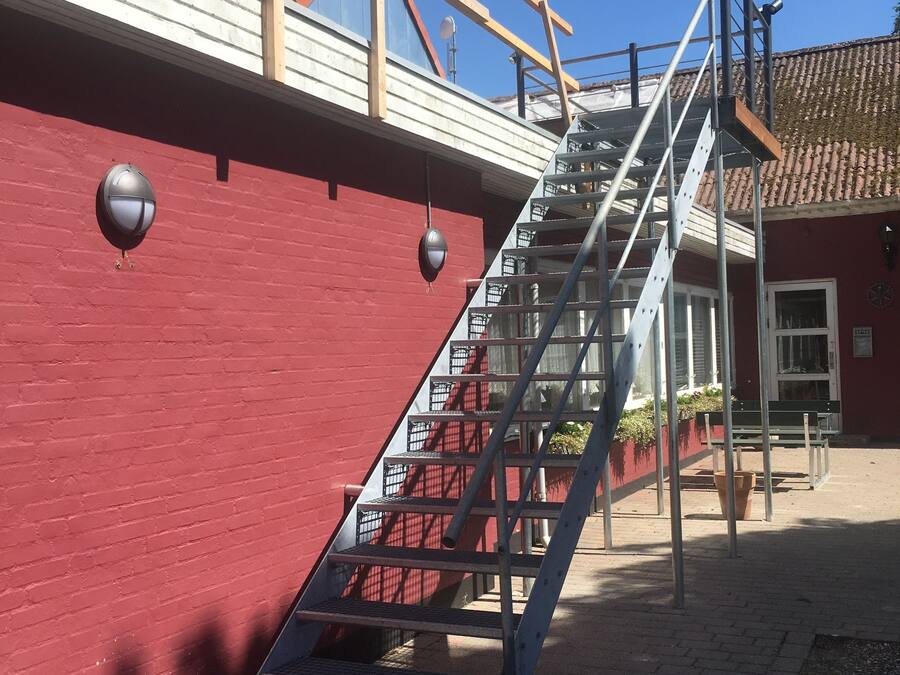 A metal staircase leading up to a red building with a tiled roof.