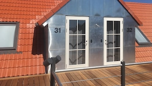 En byggnad med två dörrar märkta med numren 31 och 32, en fasad av metall och ett rött tegeltak.