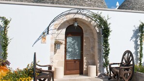 A building with stone conical roofs, a wooden door, and a stone bench. - Trulli San Leonardo (Alberobello)