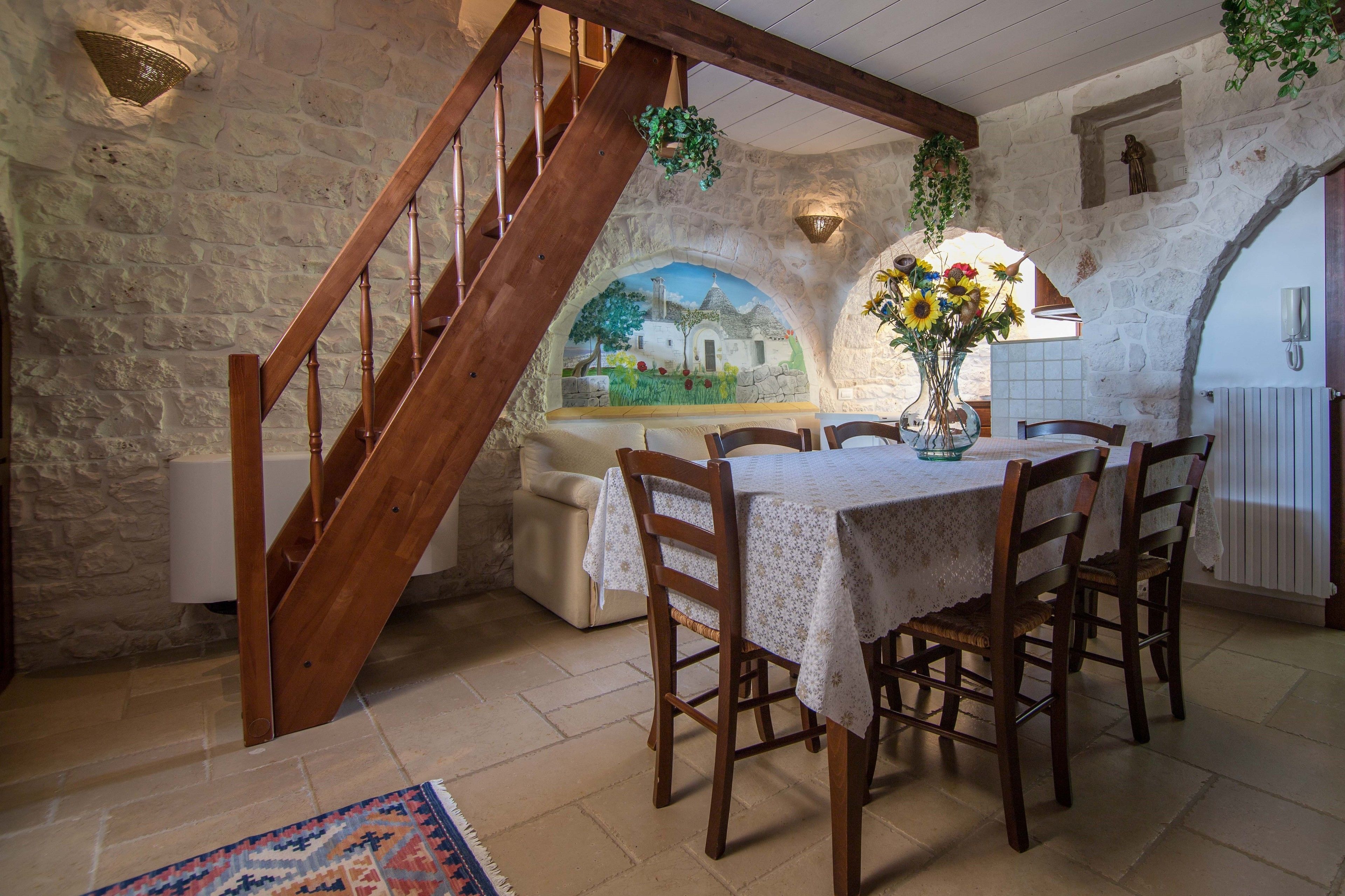 A dining area with a stone wall, wooden staircase, and a mural.
