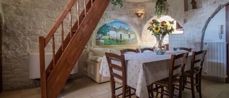 A dining area with a stone wall, wooden staircase, and a mural.