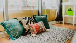 A cozy seating area with a patterned rug, a teal and black throw pillow, and a multicolored throw pillow. - Lovely Bohemian Apartment in Heart of City Life (Glasgow)