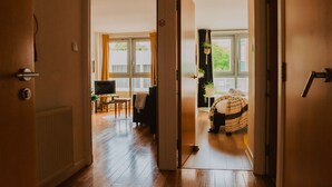 An open door leading to a living room with a television, a sofa, and a window with curtains. - Lovely Bohemian Apartment in Heart of City Life (Glasgow)