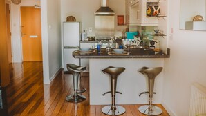 A modern kitchen with a central island, bar stools, and a coffee machine. - Lovely Bohemian Apartment in Heart of City Life (Glasgow)