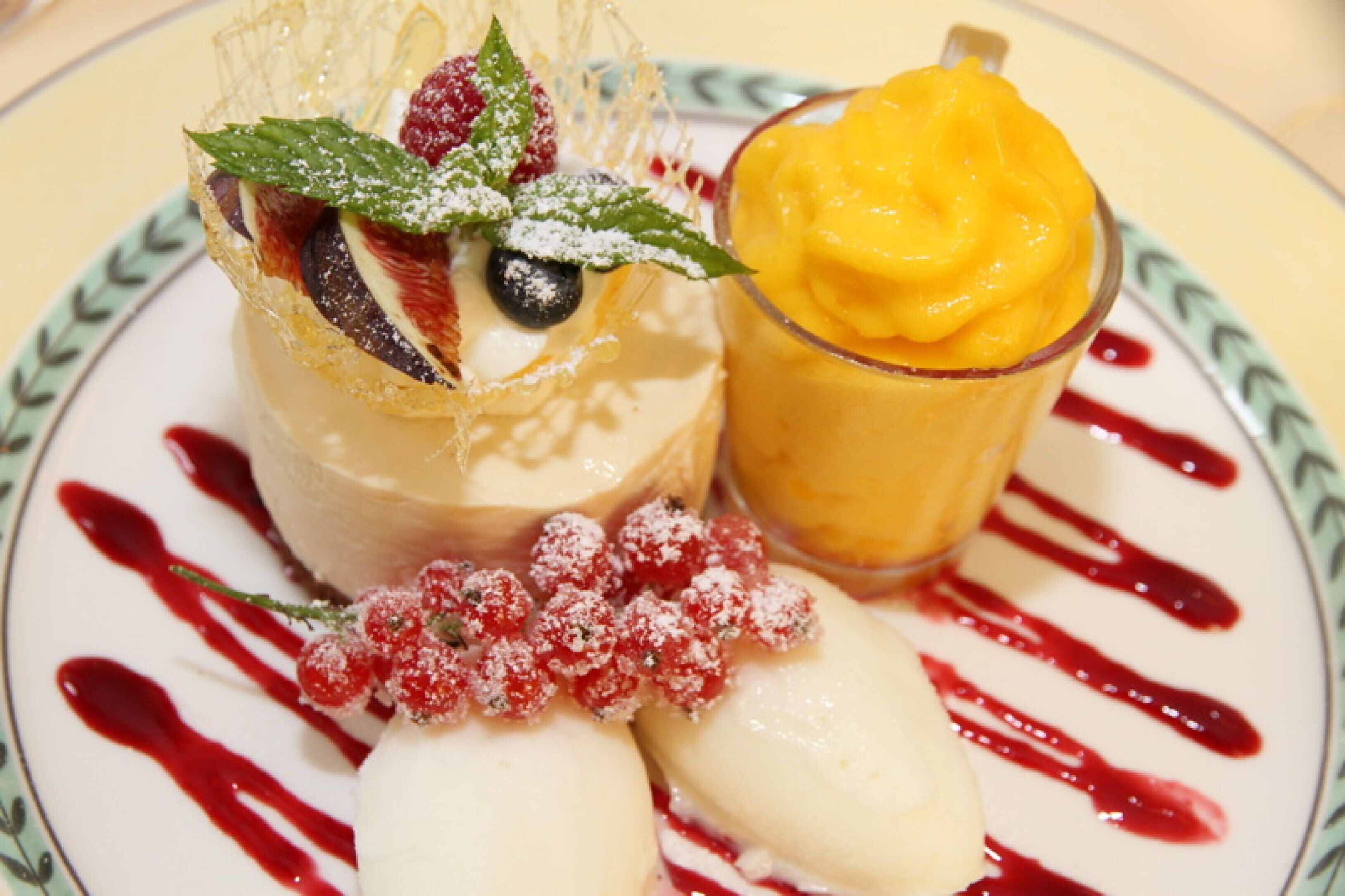 A dessert plate with a creamy dessert, a glass of mango puree, and a scoop of ice cream.