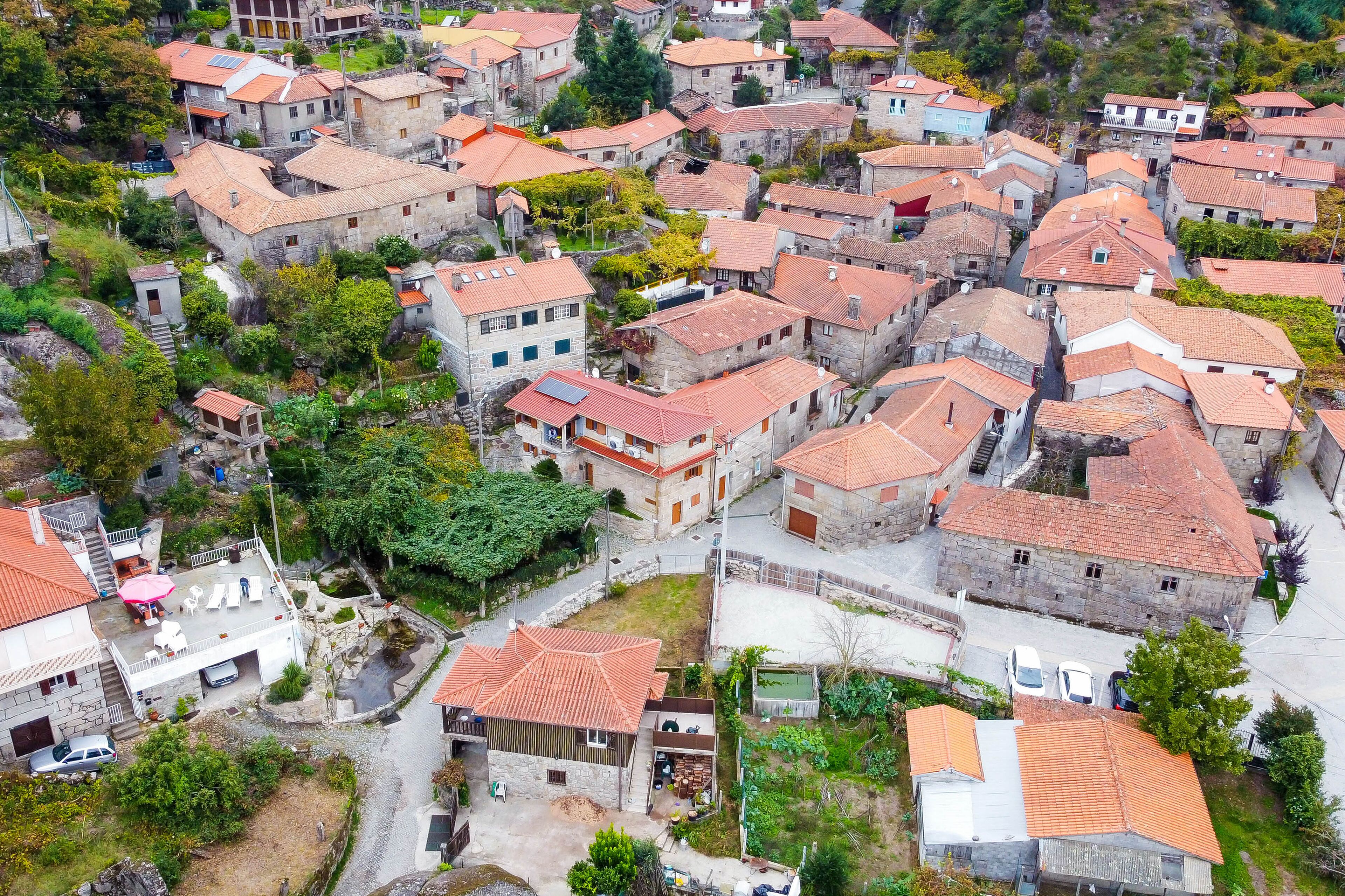 An aerial view of a historic village with stone buildings, narrow streets, and terraced gardens.