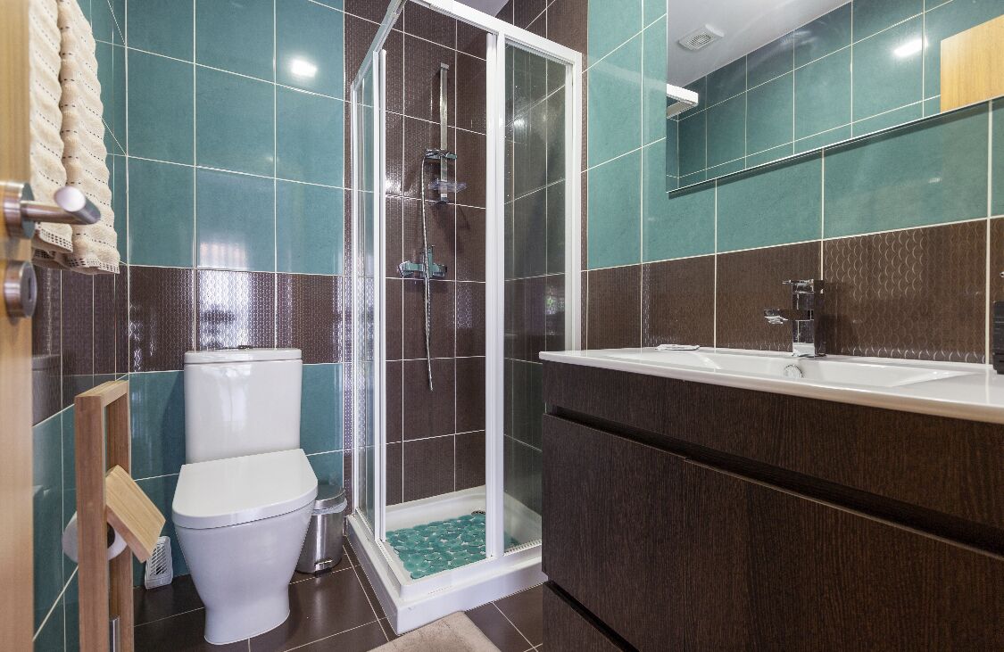 A modern bathroom with a glass-enclosed shower, a white toilet, and a vanity with a sink.