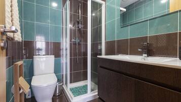 A modern bathroom with a glass-enclosed shower, a white toilet, and a vanity with a sink.