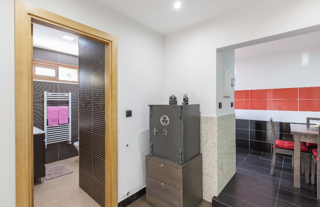 Ein modernes Badezimmer mit Handtuchhalter, einer Holztür und einem kleinen Schrank.
