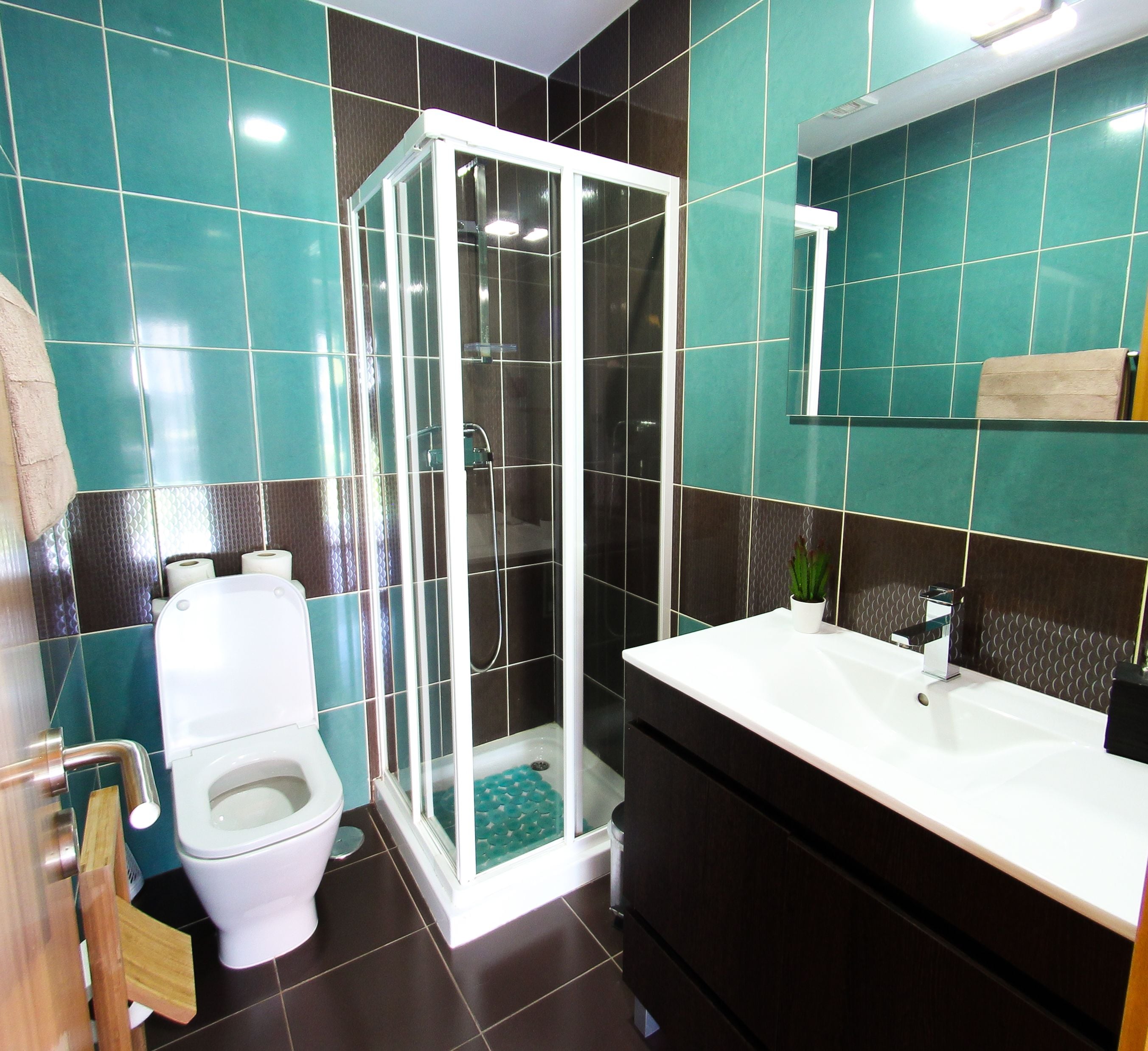 Un baño con inodoro, cabina de ducha y lavamanos con espejo.