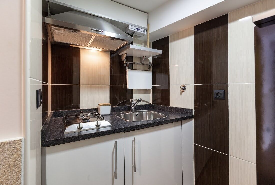 A modern kitchen with a built-in stove, a stainless steel sink, and white cabinetry.