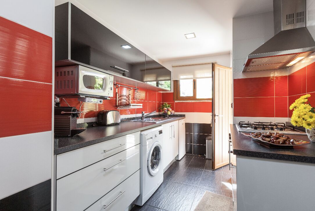Une cuisine moderne équipée d’un lave-linge, d’un four à micro-ondes et d’une cuisinière.