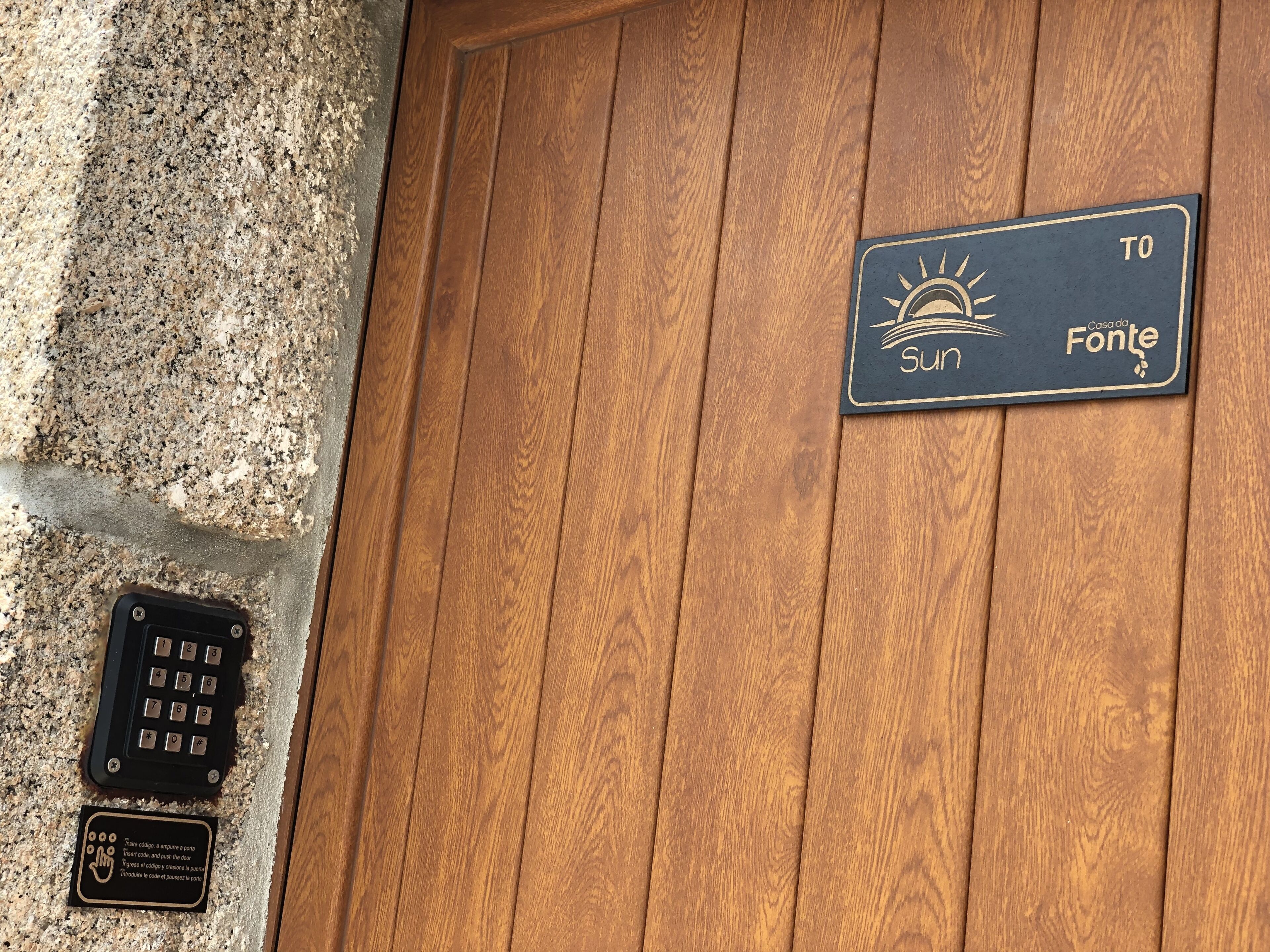 Eine Holztür mit einem Schild, das 'Casa da Fonte' anzeigt, und einem Schlüsselfeld.