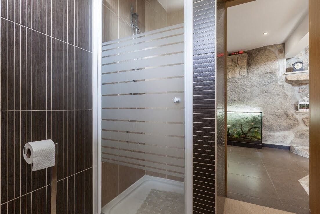 Een moderne badkamer met een douche, toilet en een glazen douchewand.