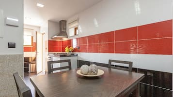 Une cuisine moderne avec des carreaux rouges et blancs, une table à manger en bois et un four encastré.