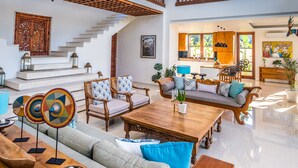 Un amplio salón con techo alto, una escalera de madera y vistas a la cocina.