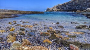 A rocky beach with clear water and a cliff.