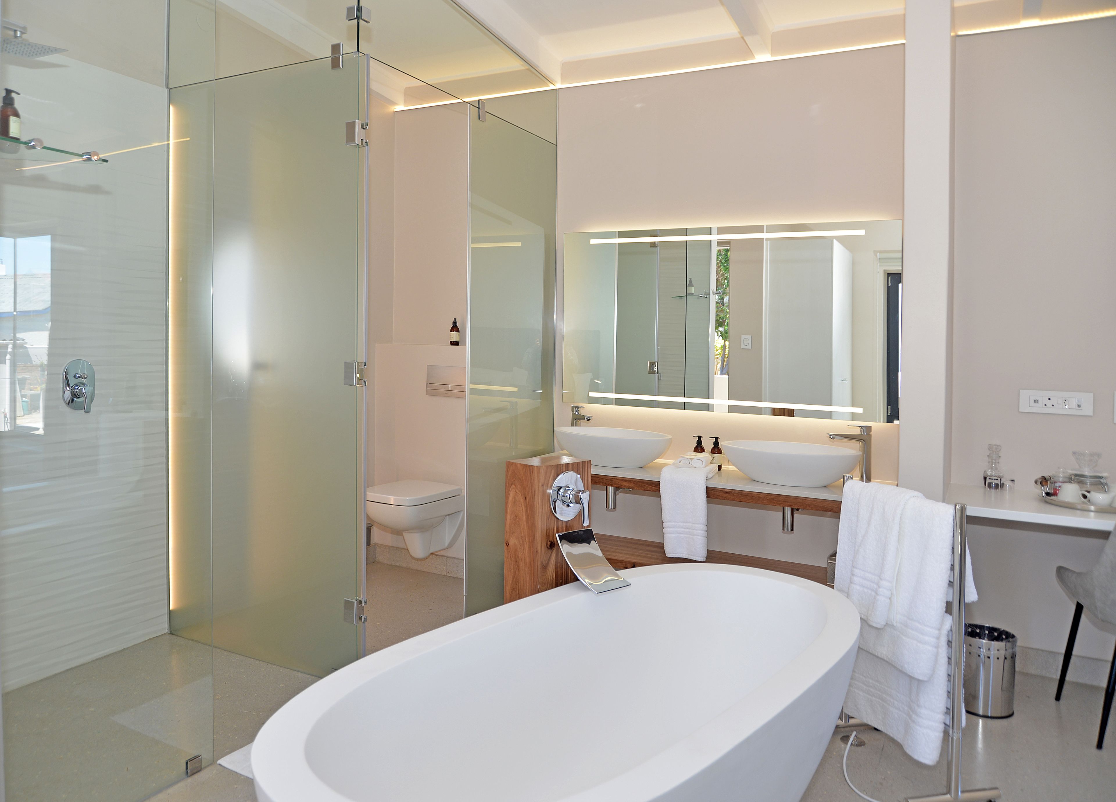 A modern bathroom with a glass-enclosed shower, a freestanding bathtub, and a double sink vanity.