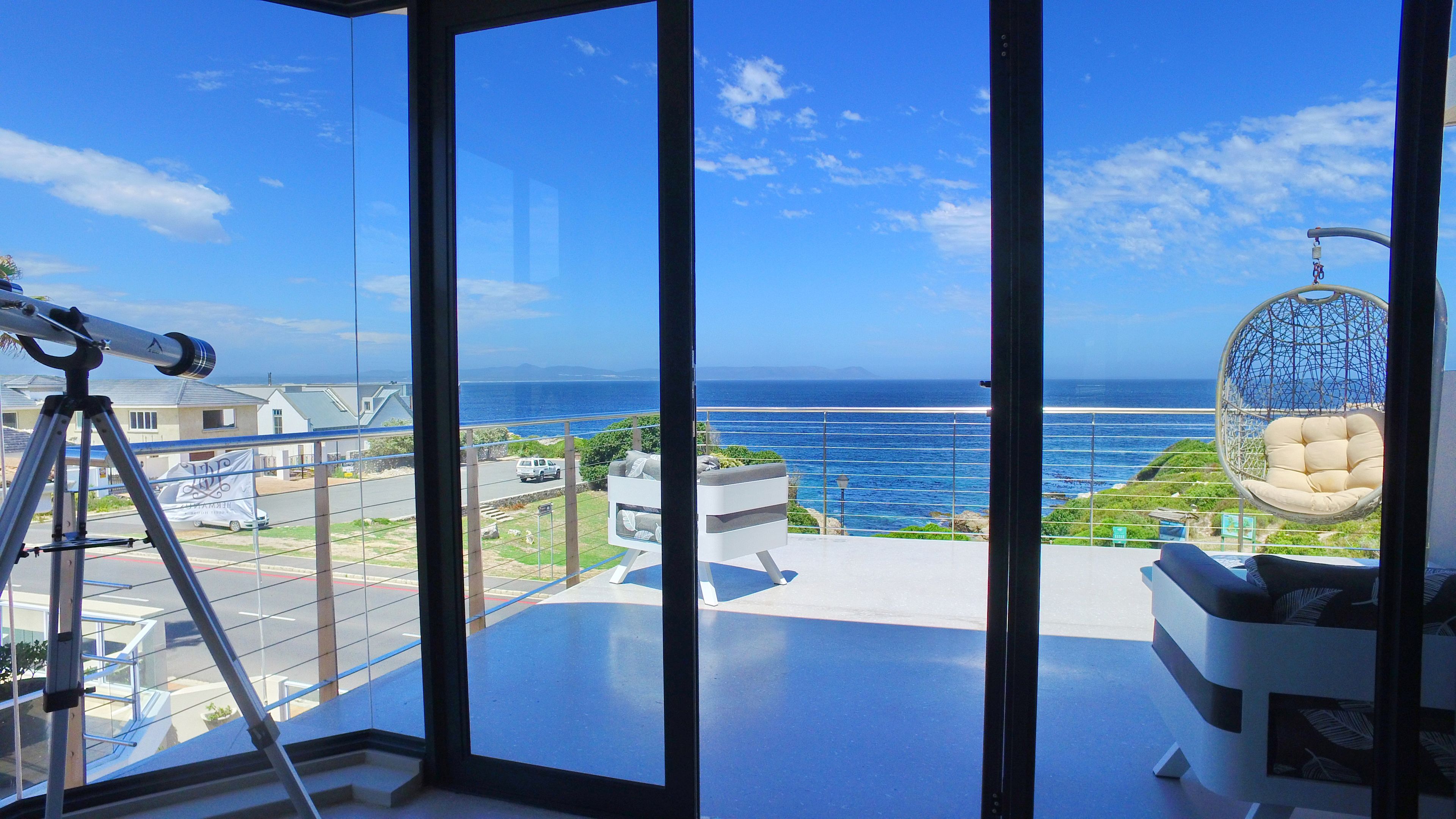 A balcony with a hanging chair, a telescope, and a view of the ocean.