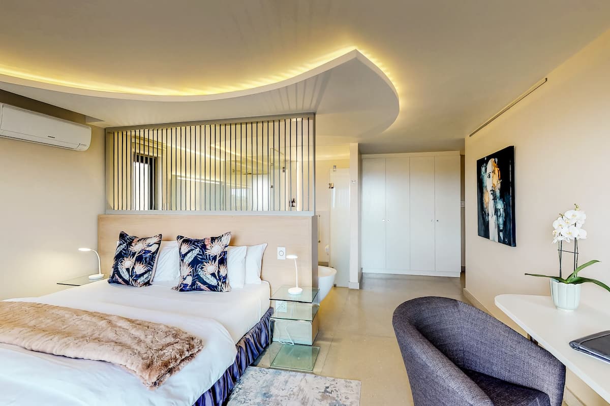 Um quarto moderno com cama, mesas de cabeceira, escrivaninha e uma cadeira.