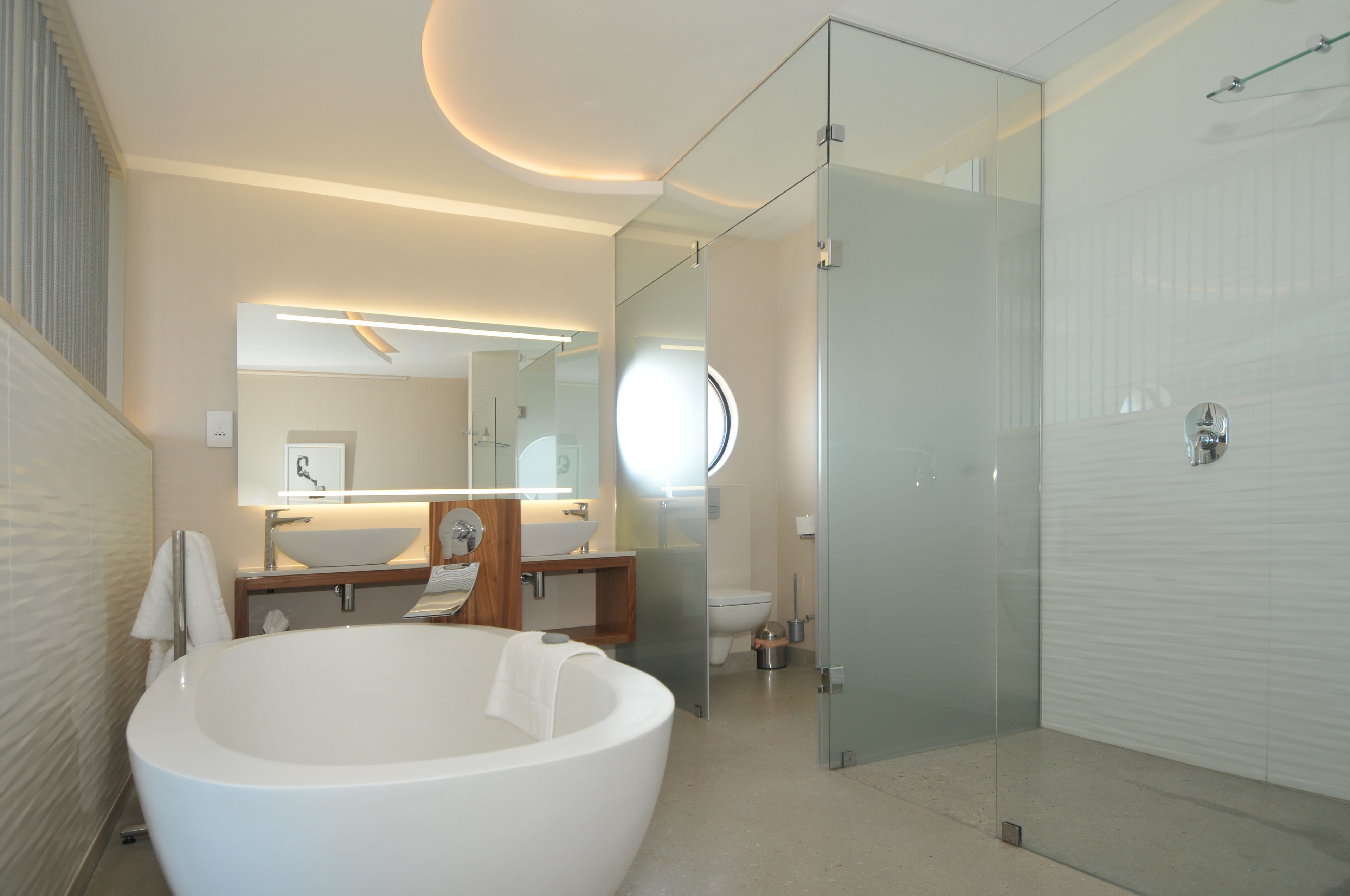 A modern bathroom with a large bathtub, a glass-enclosed shower, and a vanity with a mirror.