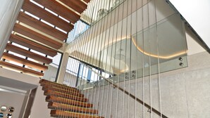 A modern staircase with wooden steps and glass railings, leading to a higher floor.