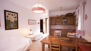 Un espacio habitable compacto con zona de comedor, kitchenette y sofá blanco.
