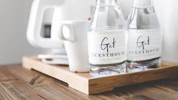 Two bottles labeled "Get Guesthouse" on a wooden tray with a white mug and a white coffee maker in the background.