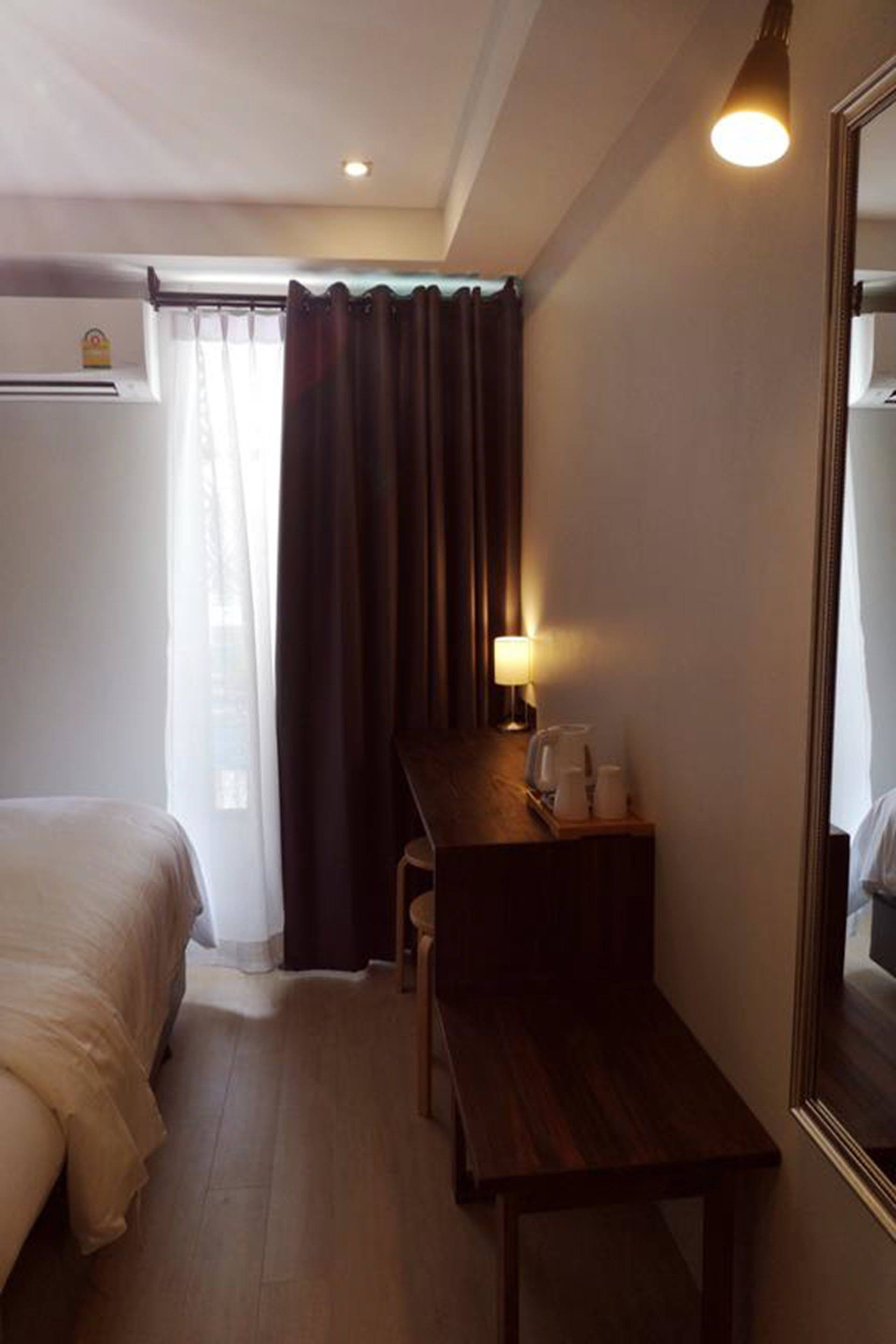 Een hotelkamer met een bed, een bureau, een stoel, een lamp en een spiegel.