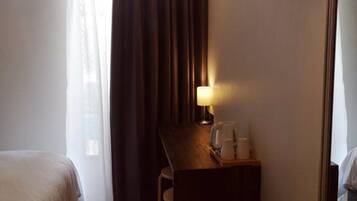 Een hotelkamer met een bed, een bureau, een stoel, een lamp en een spiegel.