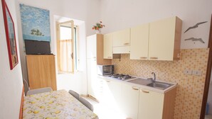 Cocina compacta con comedor, que incluye una mesa con mantel estampado de limón, un microondas, una estufa y armarios.
