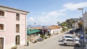 Vista de una calle con edificios, coches aparcados y un cielo despejado.