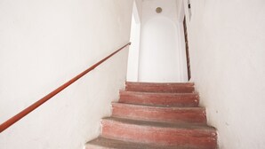 Una escalera con peldaños rojos y barandilla de madera que conduce a una puerta blanca al final.