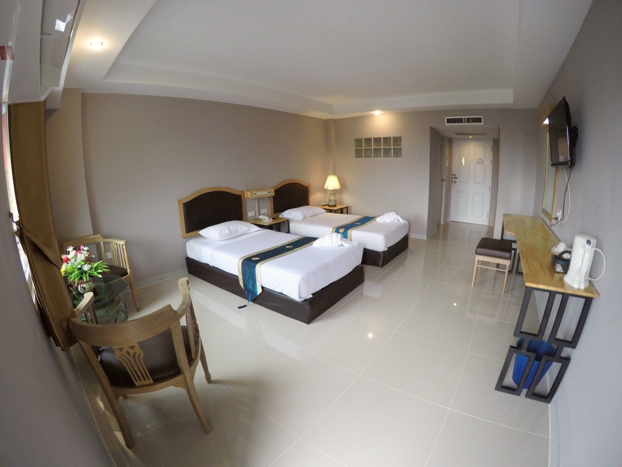 A hotel room with two beds, a desk, a chair, a TV, and a bathroom door.