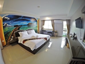 A hotel room with a large bed, a desk, a TV, and a mural on the wall. - Bcp Hotel Rayong (Ban Chang)
