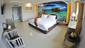 A hotel room with a large bed, a desk with a chair, a television, and a mural of a coastal scene. - Bcp Hotel Rayong (Ban Chang)