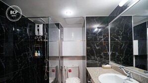 A modern bathroom with a glass-enclosed shower, a white sink, and a large mirror. - Bcp Hotel Rayong (Ban Chang)