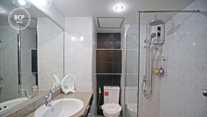 A modern bathroom with a granite countertop sink, a large mirror, a glass-enclosed shower, and a toilet with a bidet attachment. - Bcp Hotel Rayong (Ban Chang)