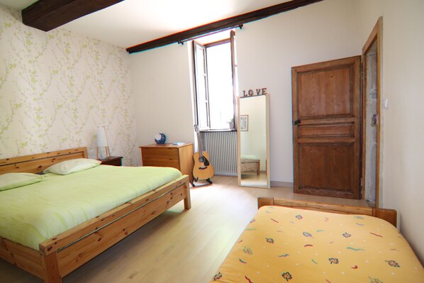 Un dormitorio con cama de madera, una mesita de noche pequeña, una guitarra y un armario.