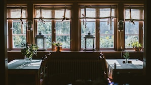 Una habitación con un ventanal grande, muebles de madera y faroles colgantes.
