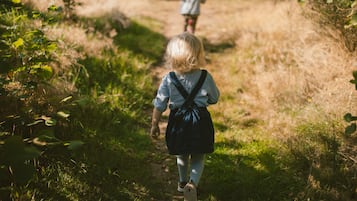 Un enfant qui marche sur un sentier herbeux, un sac à dos sur le dos.