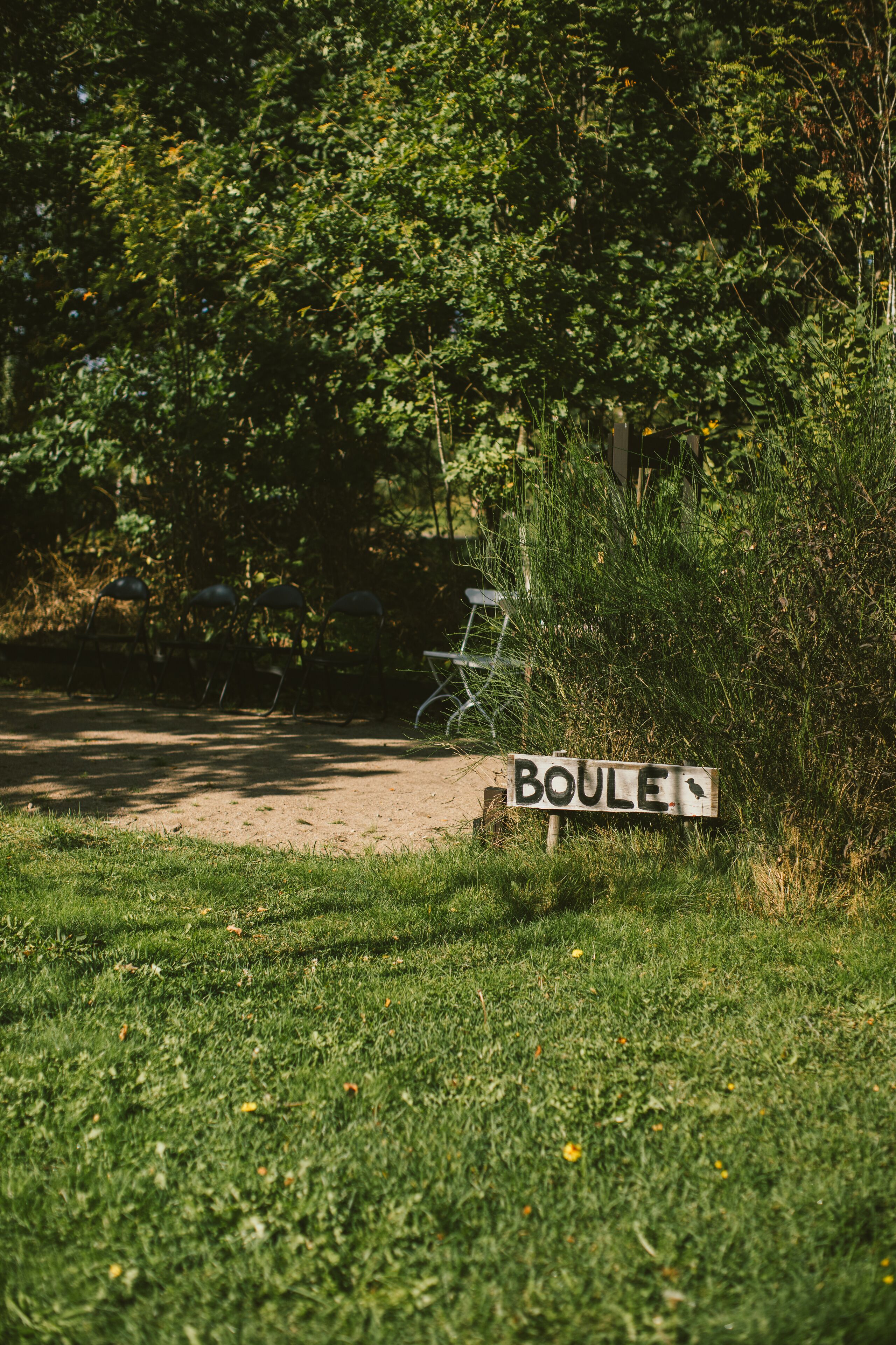 Un senyal amb la inscripció 'BOULE' en una zona verda, amb arbres i una estructura metàl·lica al fons.